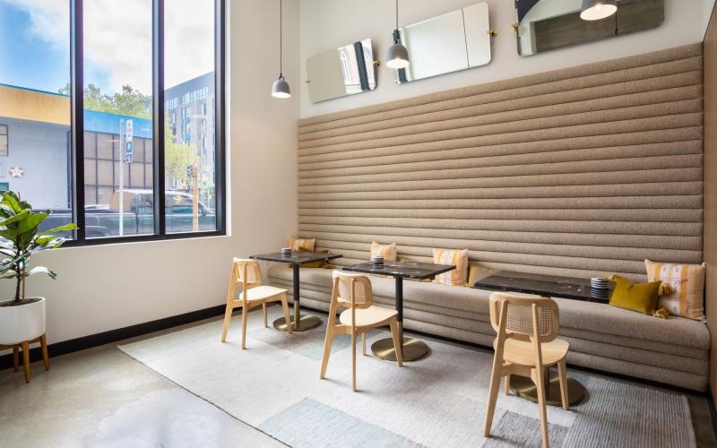 bench wall, tables and chairs next to large windows