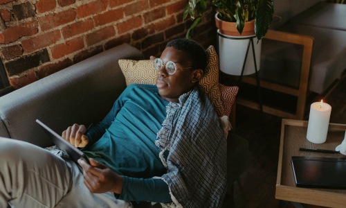a man looks at his tablet while lying on his living room couch